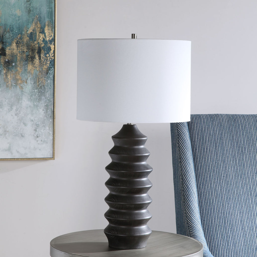 Experience the perfect fusion of modernity and lodge-inspired charm with our captivating table lamp. Crafted with meticulous attention to detail, its carved wood base exudes rustic elegance, enhanced by a lustrous black stain that gracefully reveals the subtle wood grain.- Alternate Image